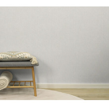 Lichte, gestructureerde behang in de kamer, gecombineerd met een zitkruk en decoratieve elementen.