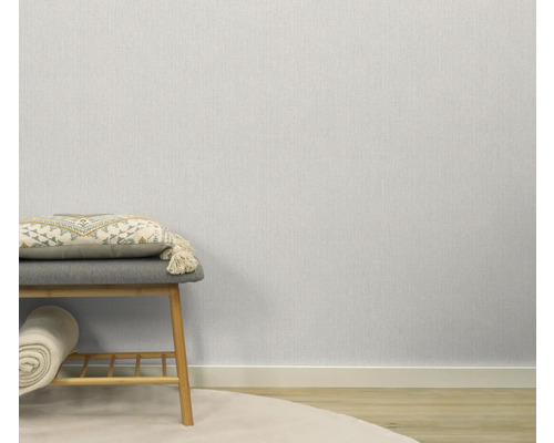 Lichte, gestructureerde behang in de kamer, gecombineerd met een zitkruk en decoratieve elementen.