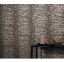 Detailopname van een muur met behang in reptielenleerlook, een kandelaartableau met kaars en bloemdecoratie