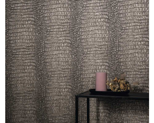 Detailopname van een muur met behang in reptielenleerlook, een kandelaartableau met kaars en bloemdecoratie