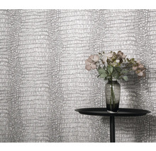 Close-up van een muur met krokodillenleer behang, een tafel en bloemenvaas