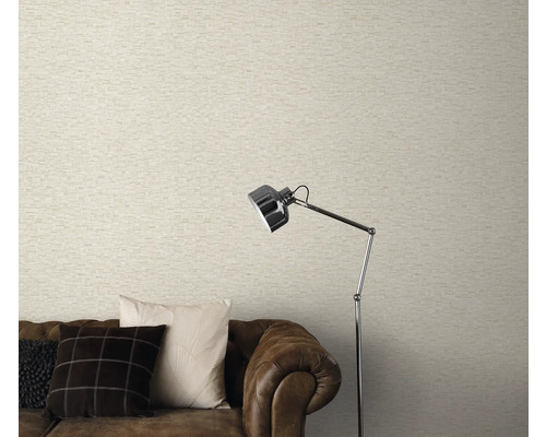 Woonkamer met licht behang in metselwerklook, bruine bank en staande lamp