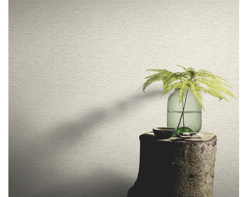 Close-up van een muur met een behang in steenlook, op een boomstronk staat een vaas met een plant.