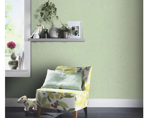 Decoratieve kamer met groen vliesbehang, fauteuil met plantenpatroon en raam met decoratie