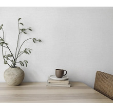 Decoratief stilleven met vaas, takken, kop en boeken op een houten tafel.