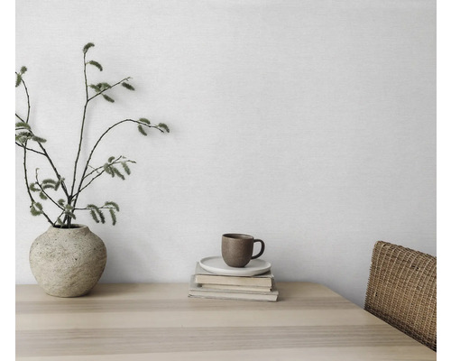 Decoratief stilleven met vaas, takken, kop en boeken op een houten tafel.
