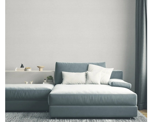 Woonkamer met grijsblauwe hoekbank, witte kussens en grijs tapijt