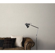 Woonkamer met bruine leren bank, kussens, staande lamp en beige behang