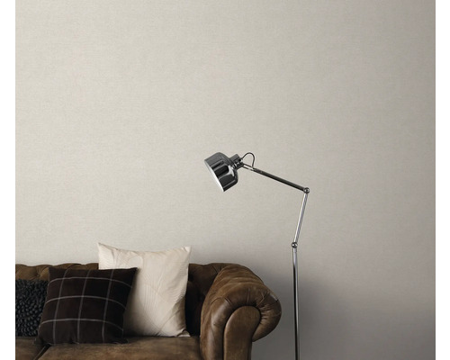 Woonkamer met bruine leren bank, kussens, staande lamp en beige behang