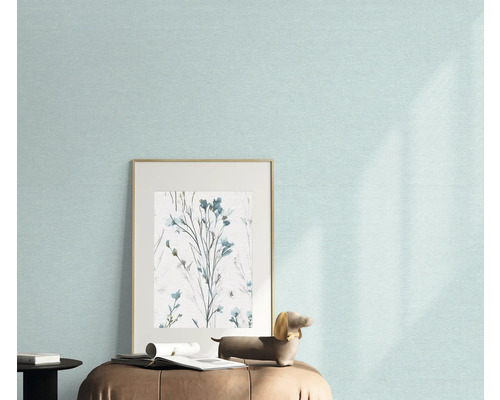 Close-up van een muur met licht behang, een ingelijste afbeelding met bloemenmotief en een decoratief figuur