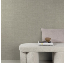 Gedetailleerde opname van een beige structuurbehang met bank, kussen en decoratie