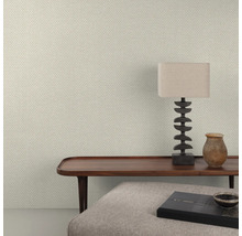 Close-up van een wand met visgraatbehang, een houten tafel, een lamp en decoratieve objecten.