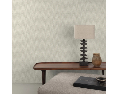 Close-up van een wand met visgraatbehang, een houten tafel, een lamp en decoratieve objecten.