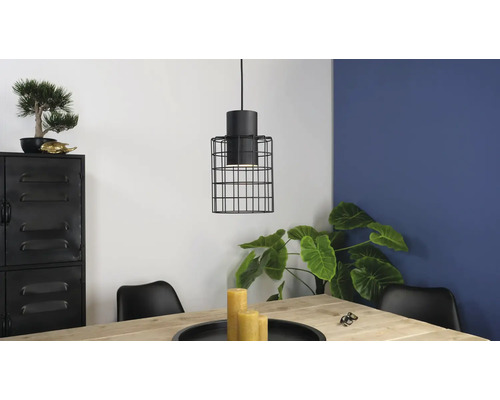 Scene met een hanglamp met een kooischerm boven een houten tafel