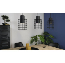 Drie hanglampen met zwarte draadkooi boven een eettafel in een lichte ruimte