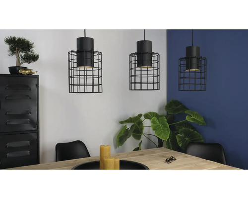 Drie hanglampen met zwarte draadkooi boven een eettafel in een lichte ruimte