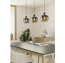 Drie hanglampen met ronde glazen kappen boven een eettafel.