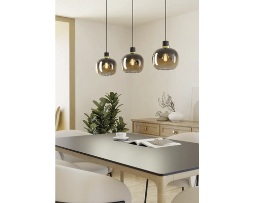 Drie hanglampen met ronde glazen kappen boven een eettafel.