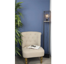 Fauteuil met boek en bril naast staande lamp en kamerplant