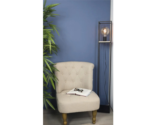 Fauteuil met boek en bril naast staande lamp en kamerplant