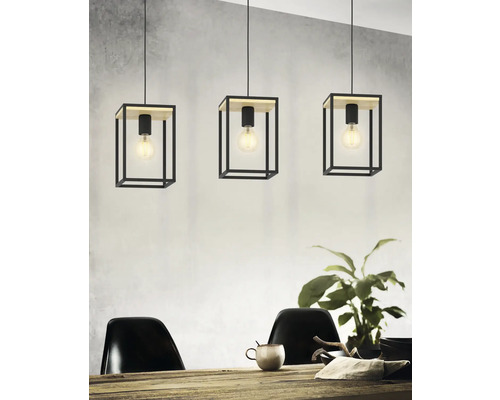 Drie hanglampen met kubusvormige lampenkappen van metaal en houten elementen boven een eettafel.