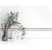 Lichte, georganiseerde decoratieve scène met eucalyptustakken in een keramieken vaas, geurstokjes, een kaars en een boogsculptuur voor sierlijsten.