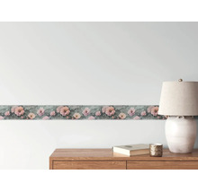 Behangrand met roze bloemenpatroon op een wand boven een houten dressoir met een tafellamp.