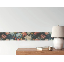 Behangrand met bloemenpatroon op een muur boven een houten dressoir met een lamp en boek.
