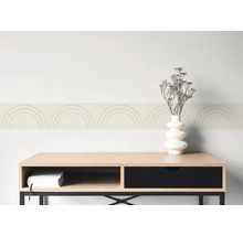 Behangrand met boogpatroon op een muur boven een dressoir van hout met een vaas en droogbloemen.