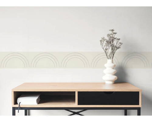 Behangrand met boogpatroon op een muur boven een dressoir van hout met een vaas en droogbloemen.