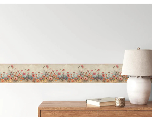 Behangrand met klaproosmotief op een muur boven een houten ladekast met tafellamp in een lichte kamer.