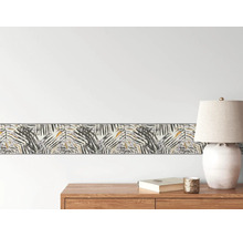 Lichte en georganiseerde scène met een behangrand in palmblad-ontwerp op de muur boven een houten dressoir met een tafellamp.