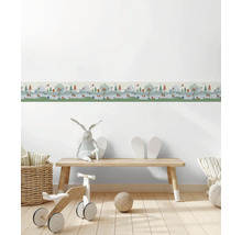 Behangrand voor de kinderkamer met bosmotief, bomen en dieren in een lichte kamer met houten bankje en speelgoed.