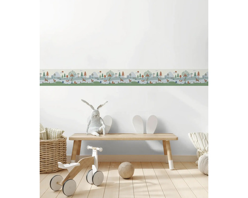 Behangrand voor de kinderkamer met bosmotief, bomen en dieren in een lichte kamer met houten bankje en speelgoed.