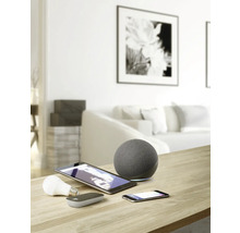 Foto van een woonkamer met smart home apparaten zoals luidspreker, tablet, smartphone en lamp op een tafel.