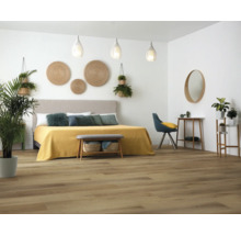 Slaapkamer met bed, bank, stoel, planten en houten vloer