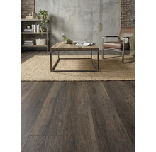 Woonkamer met houten vloer, vloerkleed, tafel, fauteuil en plank