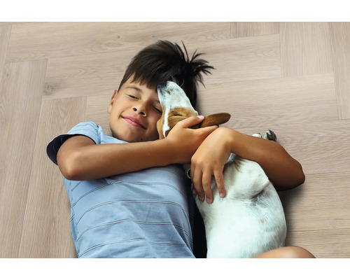 Jongen knuffelt hond op houten vloer