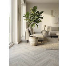 Lichte woonkamer met lichtgrijze visgraat parketvloer, potplant, bank, tapijt en kunst