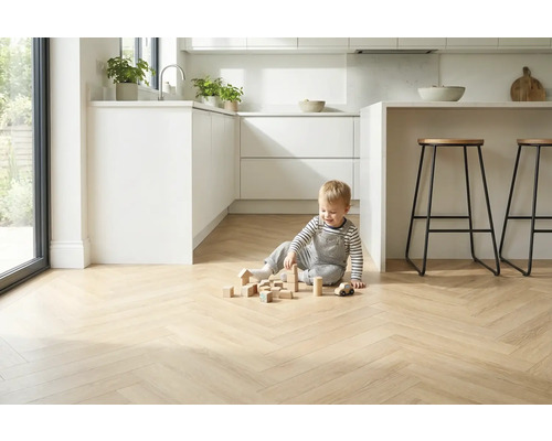 Lichte visgraatparketvloer in een moderne keuken met spelend kind