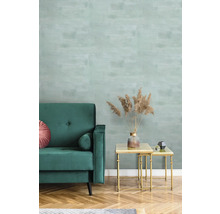 Woonkamer met groene bank, salontafel en behang met patroon.