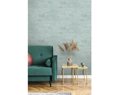 Woonkamer met groene bank, salontafel en behang met patroon.
