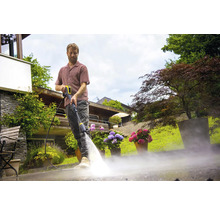 Man maakt terras schoon met hogedrukreiniger in de tuin.