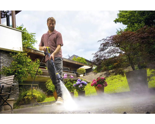 Man maakt terras schoon met hogedrukreiniger in de tuin.