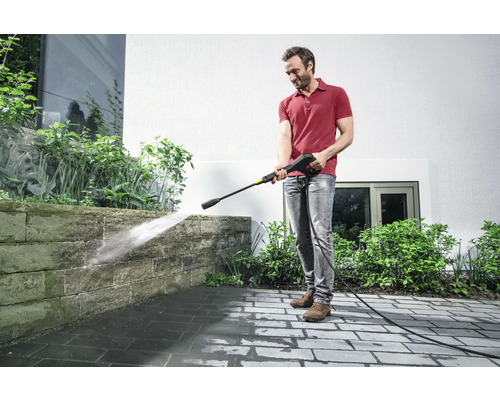 Man reinigt stenen muur met een hogedrukreiniger buitenshuis.
