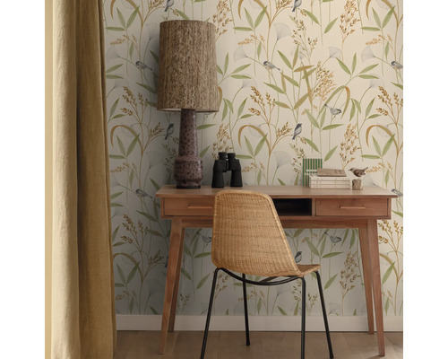 Een studeerkamer met een bureau, stoel, lamp, verrekijker en behang met print.