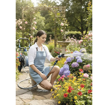 Vrouw besproeit bloemen met een tuinspuit in een bloeiende tuin.