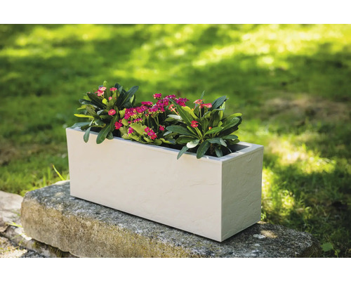 Rechthoekige kunststof plantenbak met bloemen op stenen muur