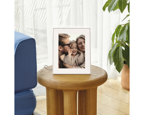 Digitale fotolijst op een ronde houten bijzetter in de woonkamer, toont een familiefoto