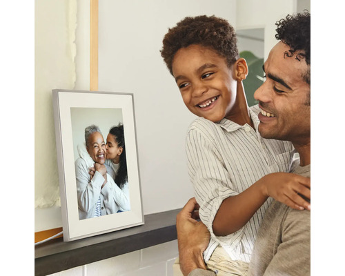 Digitale fotolijst op een plank, bekeken door een glimlachende vader en zoon.